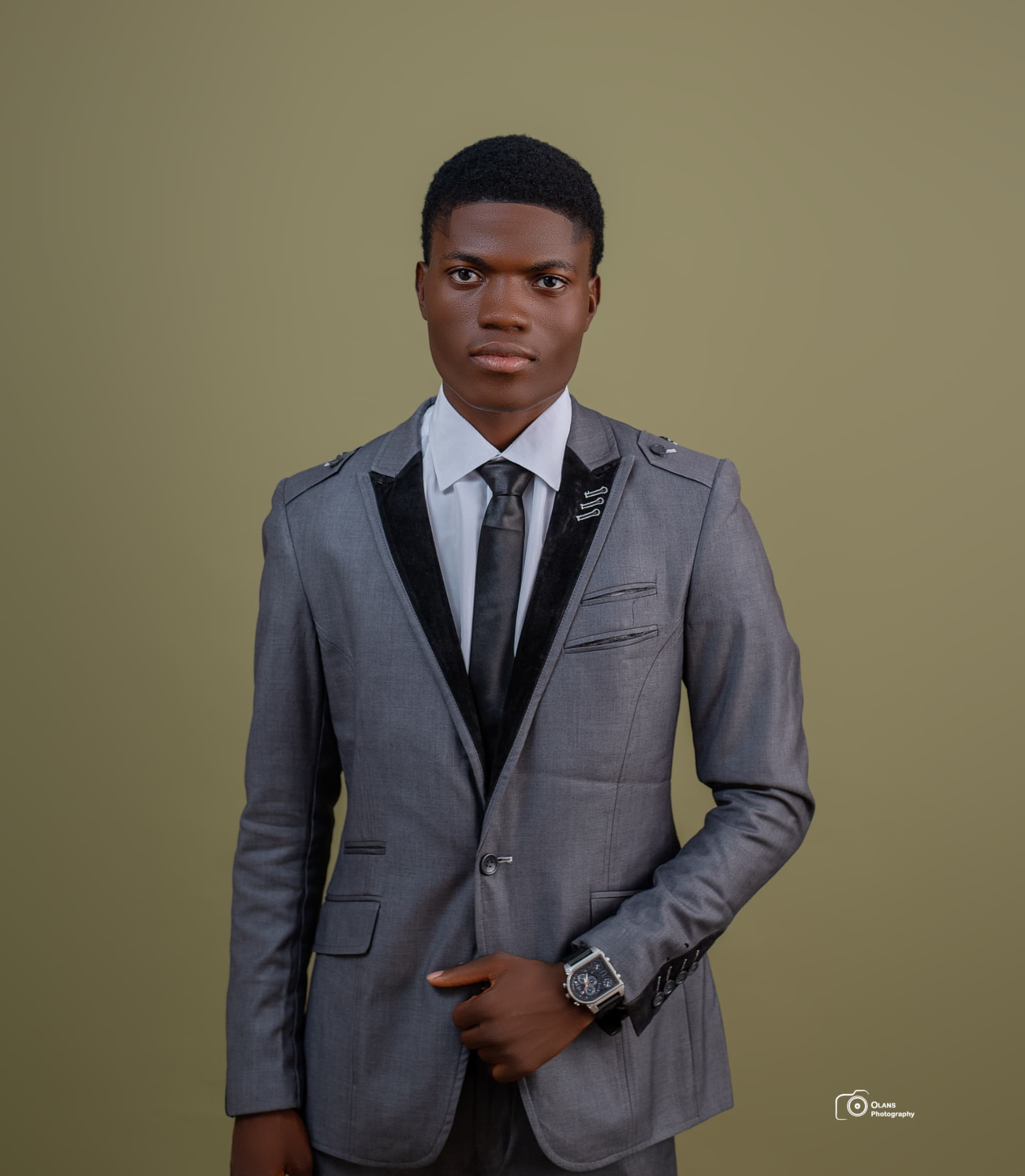 OGM in a grey suit with black velvet lapels and a black tie
