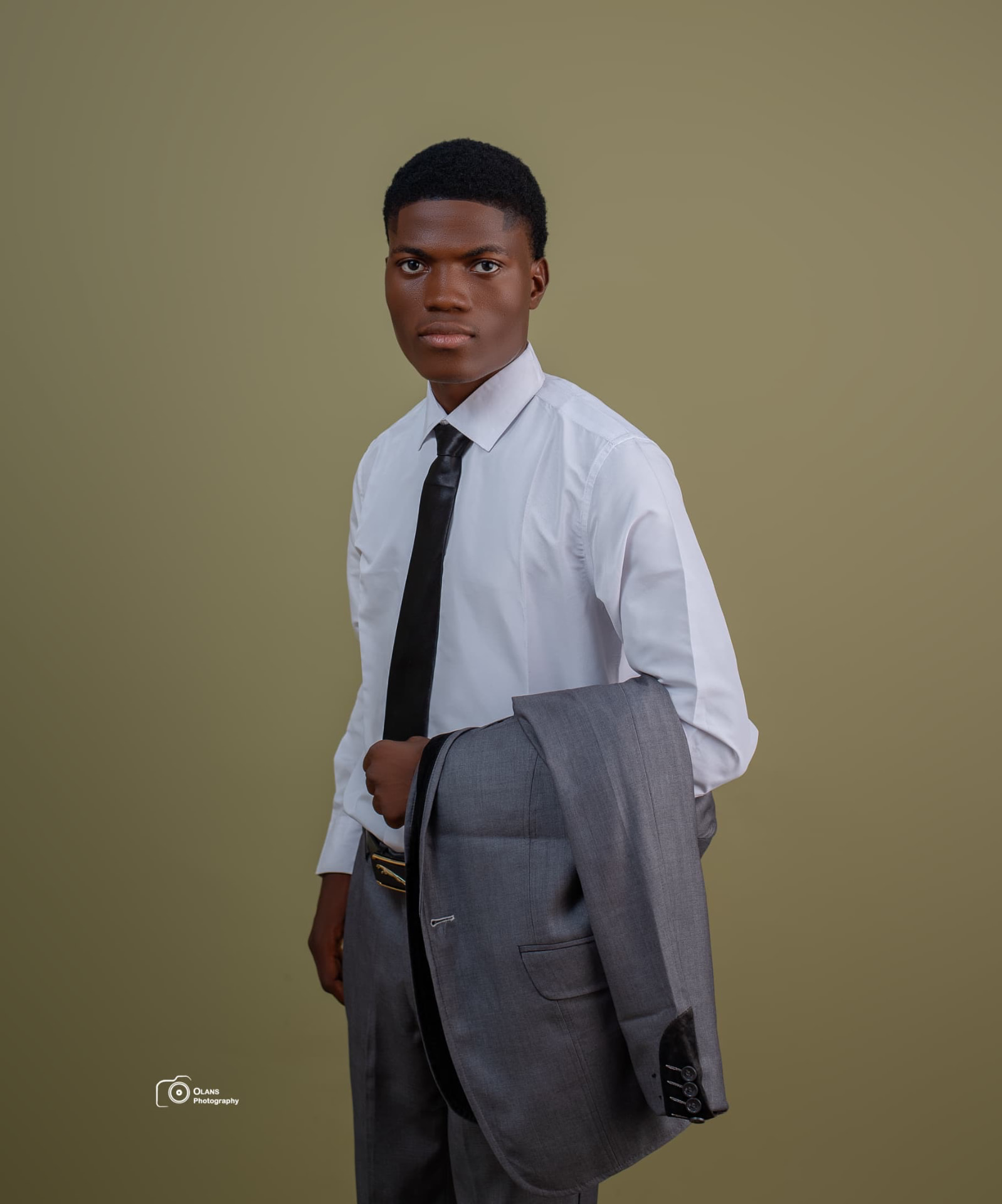 OGM in a white shirt and black tie, grey suit jacket over his arm
